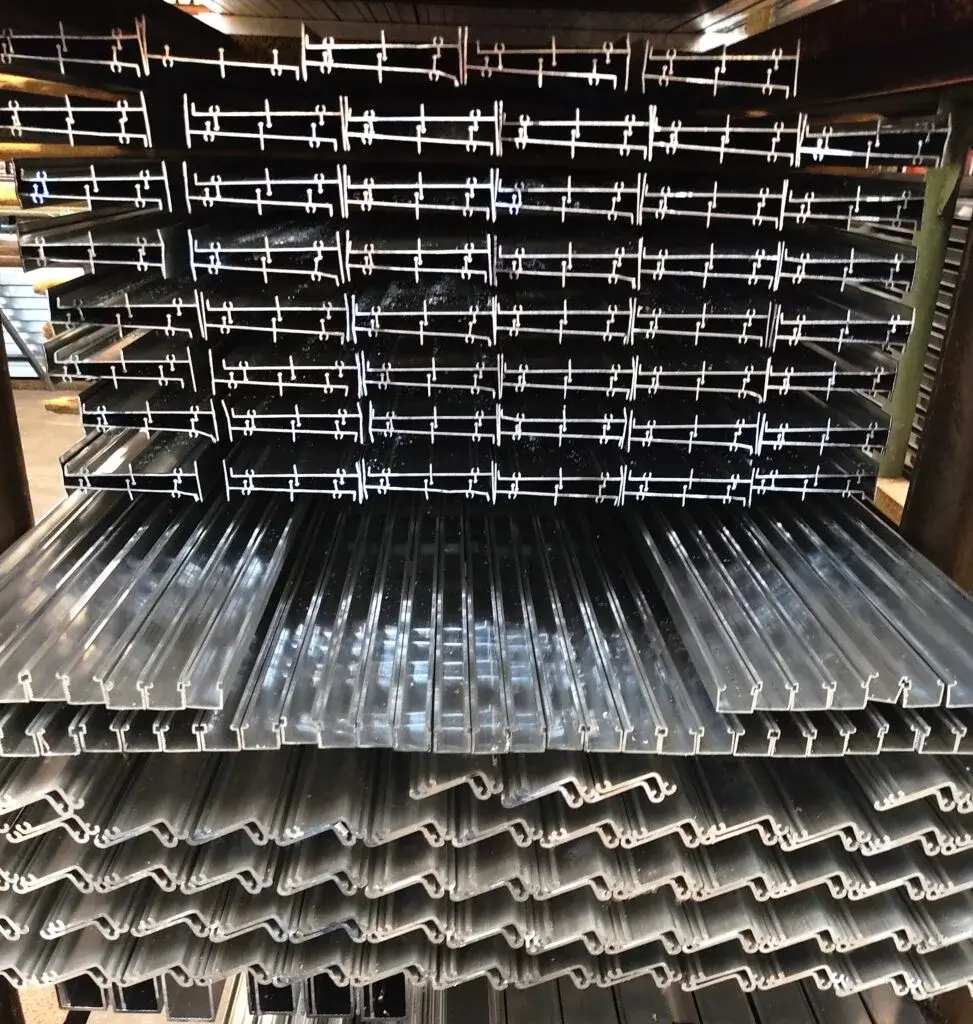 Large inventory of aluminum extrusion profiles stored in manufacturing facility for commercial building projects